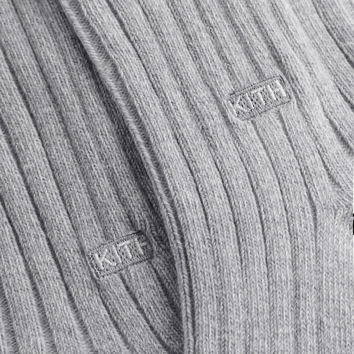 Close-up of white KITH box labels on the ribbed light grey cotton socks