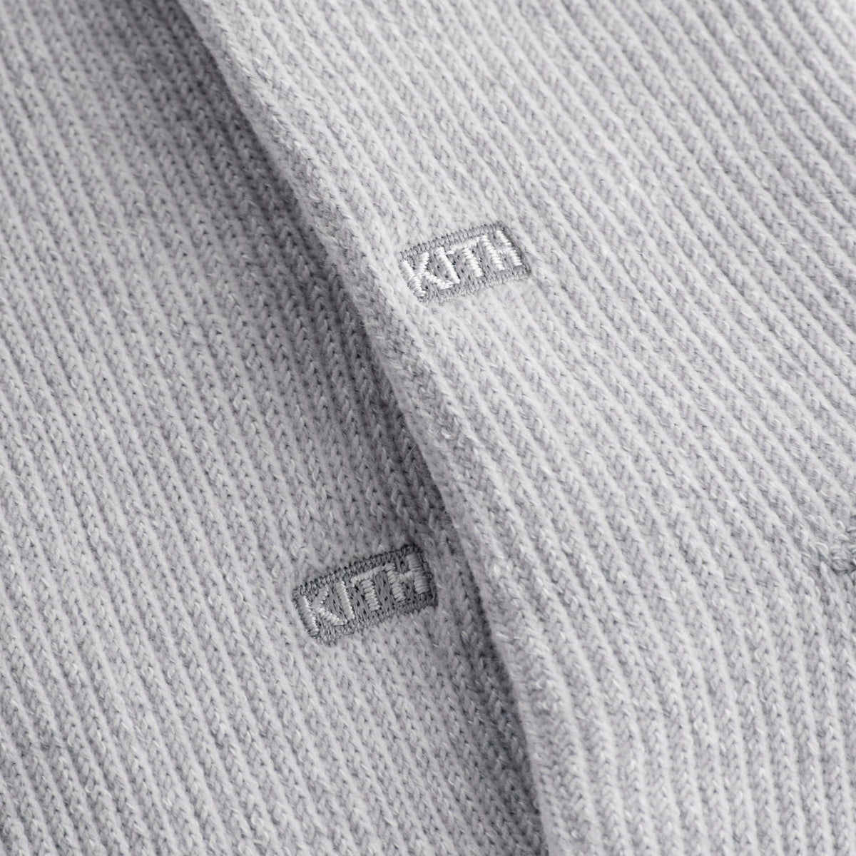 Close-up of white KITH box labels on the plain light grey cotton socks