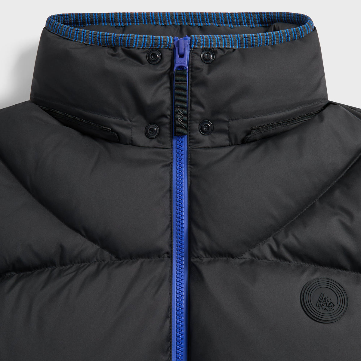 Close-up of the collar, blue zip and tonal badge on the black Corey puffer