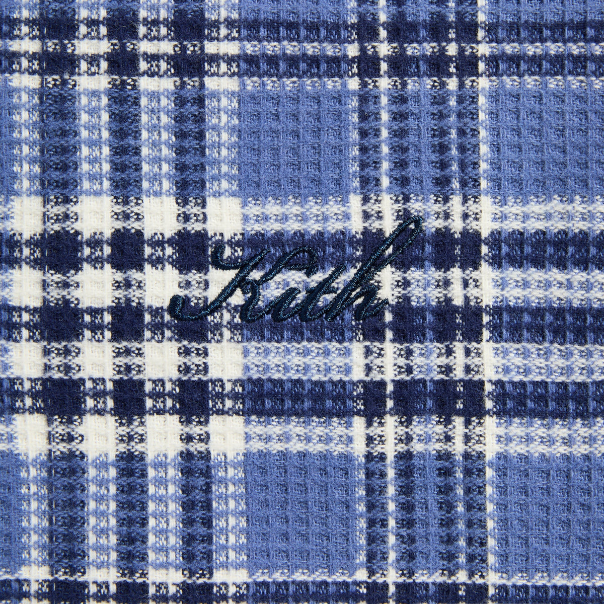 Close-up of the navy 'Kith' script on the blue plaid waffle side of the Khenny hoodie