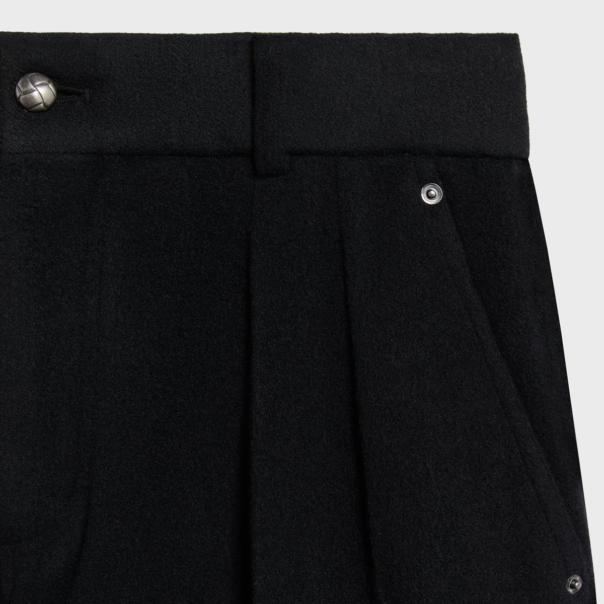 Close-up of the metal waistband button and front pleat on the black Brett trouser